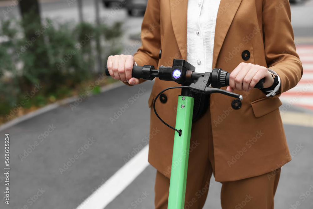 Businesswoman riding electric kick scooter on city street, closeup. Space for text