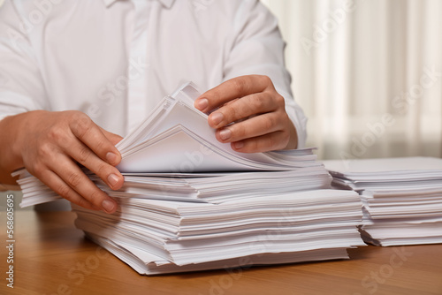 Man stacking documents at table in office, closeup