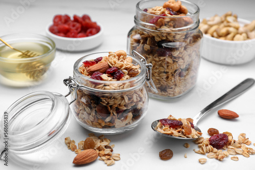 Fototapeta Naklejka Na Ścianę i Meble -  Jars of tasty granola with nuts and dry fruits on white marble table