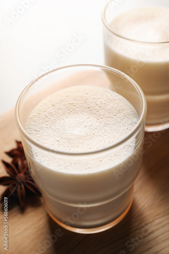 Glasses of delicious eggnog with anise on table, closeup