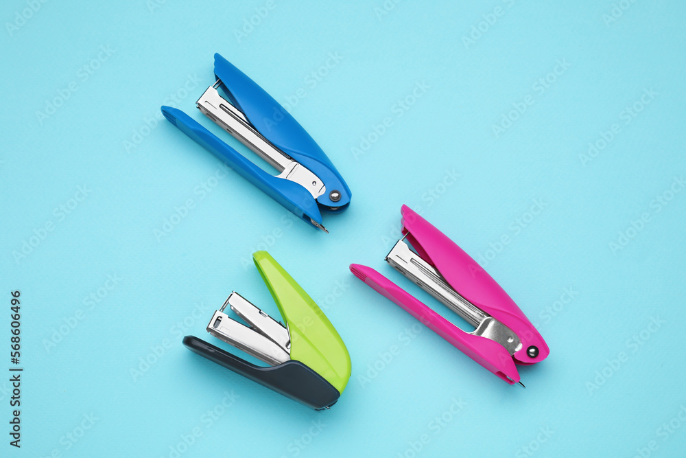 New bright staplers on light blue background, flat lay. School stationery New bright staplers on light blue background, flat lay. School stationery