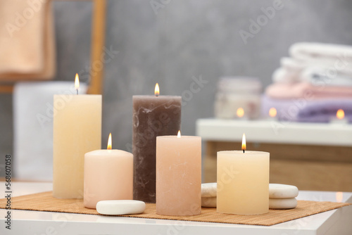Beautiful spa composition with burning candles and stones on white table in wellness center