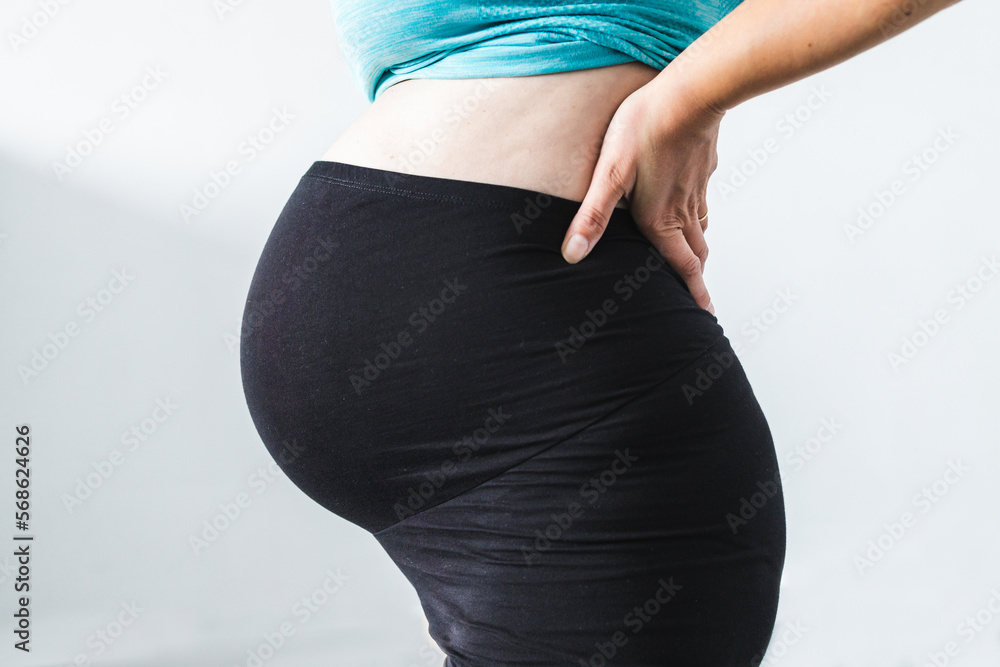 pregnant woman touching her bump in the latest stage of pregnancy, mid