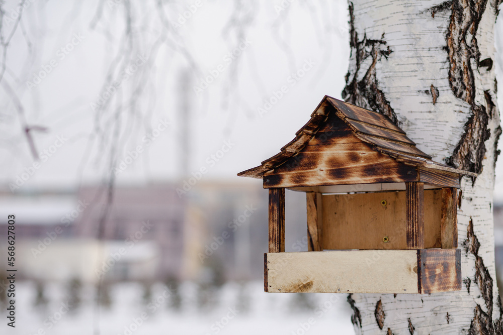 Wooden bird feeder. Birds feeder covered with snow at winter time, helping birds in winter. Wooden bird feeder with seeds handging from tree in winter garden. Wooden bird feeder. Birds feeder covered with snow at winter time, helping birds in winter. Wooden bird feeder with seeds handging from tree in winter garden.
