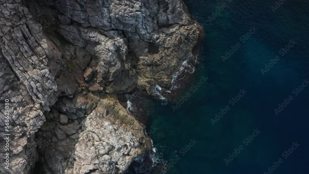 Drone Top Down Shot on Rocky Cliffside with waves crashing onto it Drone Top Down Shot on Rocky Cliffside with waves crashing onto it