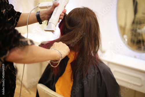  女性の髪にドライヤーをかける男性美容師