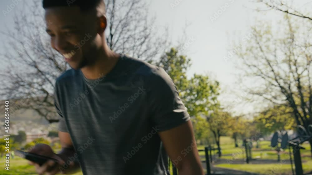 Young black man smiling and using mobile phone while taking a break in park Young black man smiling and using mobile phone while taking a break in park