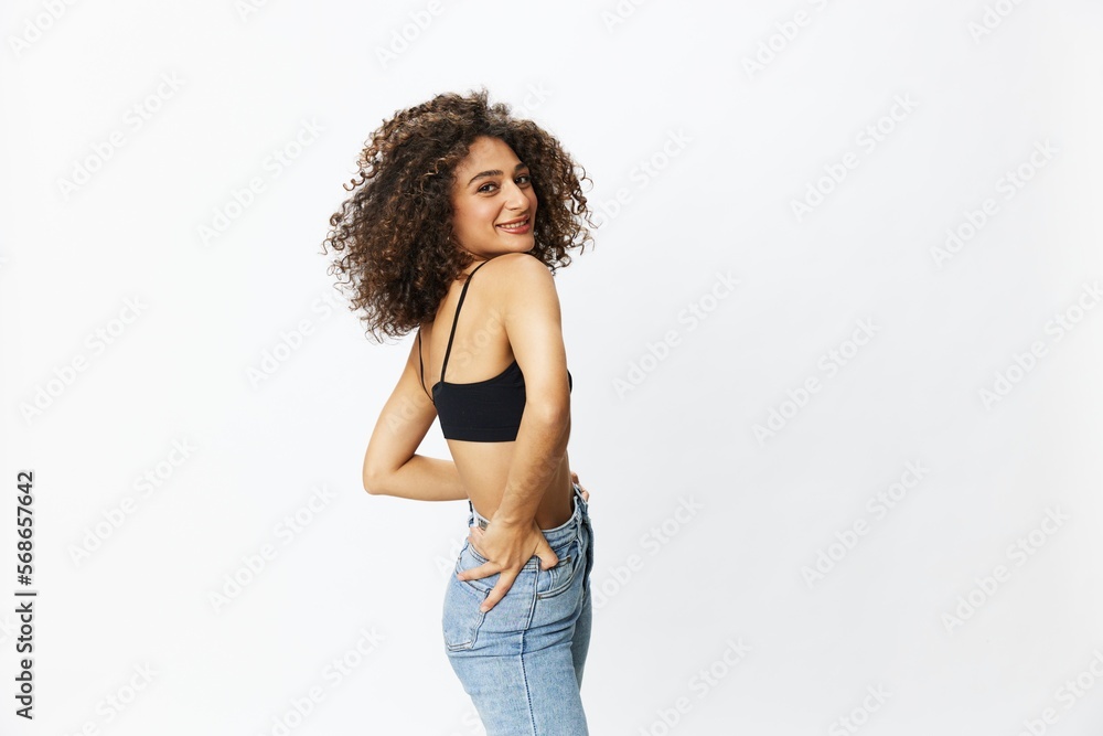 Beautiful woman with curly afro hair posing on a white isolated background smile happiness in jeans and black top emotion, hand signs, copy space Beautiful woman with curly afro hair posing on a white isolated background smile happiness in jeans and black top emotion, hand signs, copy space