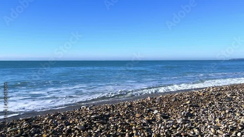 Powerful sea waves are crashing on the Black Sea coast. Sea waves splash on the beach with pebbles in the rays of the sun. Russia, Agoi photo