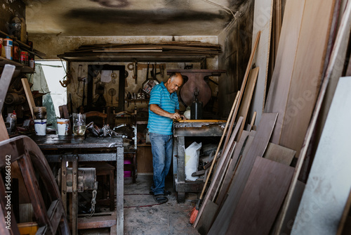 Hispanic Senior man carpenter making wooden window in his workshop in Mexico Latin America