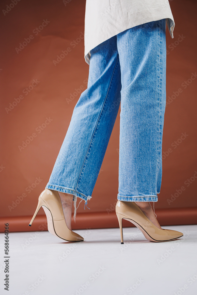 Close-up of female legs in blue jeans and fancy beige high heels. Women's  leather pumps. Stock-Foto | Adobe Stock