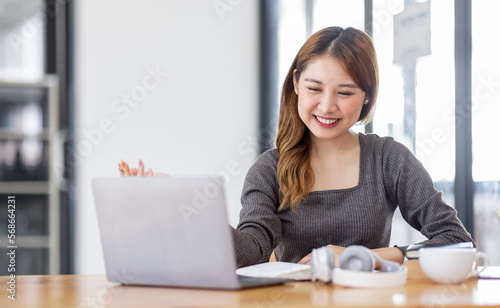 Young adult happy smiling Hispanic Asian student video calling on laptop or doing video chat by webcam in university campus or virtual at office. College female student learning remotely.