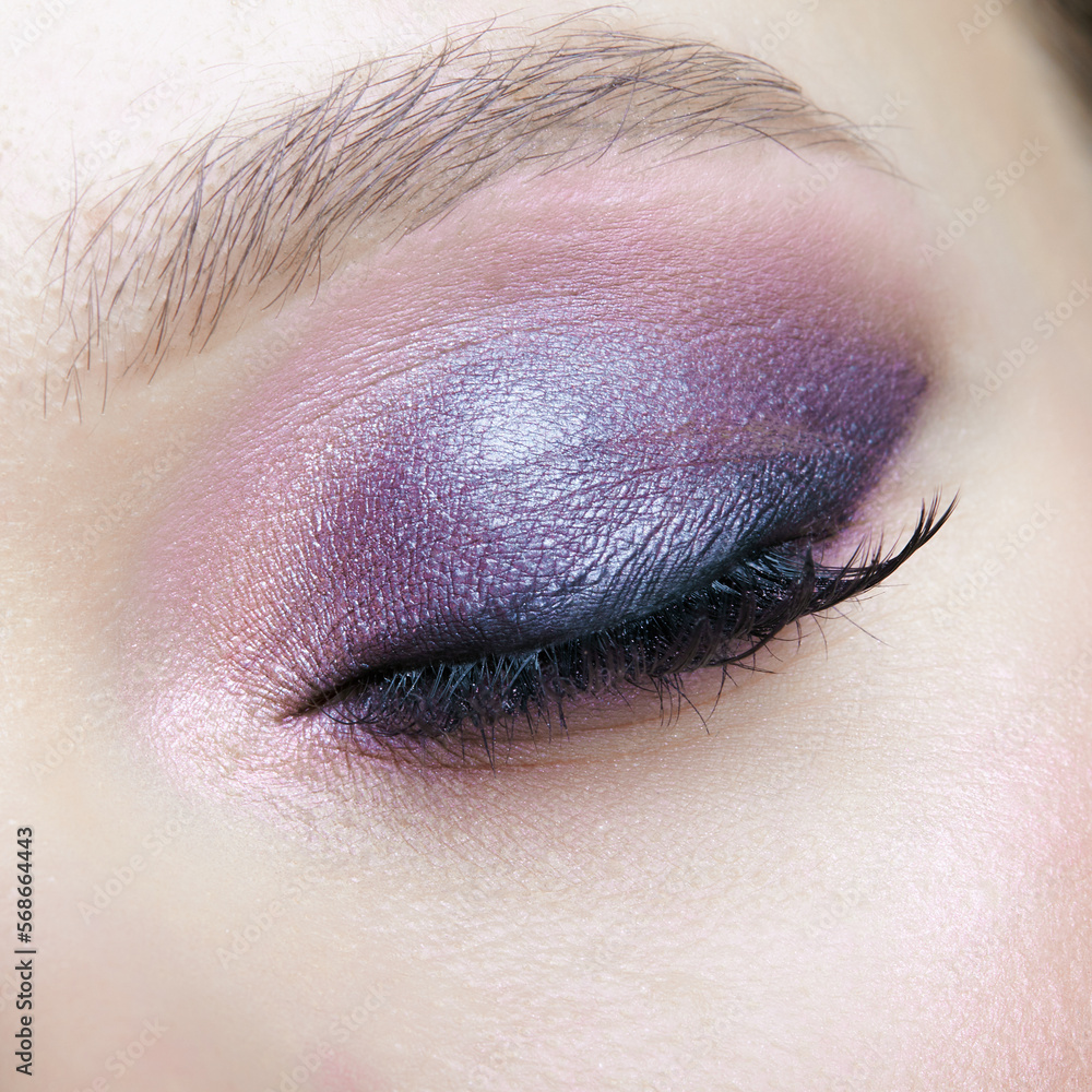 Obraz premium Closeup macro shot of human female eye. Woman with lilac beauty eyes makeup.