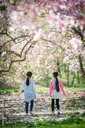 Two young asian girls in a garden surrounded by magnolia blossom tree