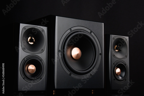 Two sound speakers and subwoofer on dark background. Set for listening music. Audio equipment