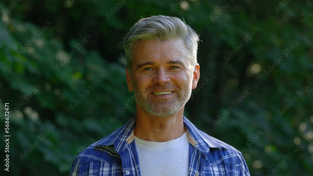 Portrait of the happy eco activist standing in the park. Close up view of middle aged handsome fermer looking straight and smiling to camera outside. Portrait of the happy eco activist standing in the park. Close up view of middle aged handsome fermer looking straight and smiling to camera outside.