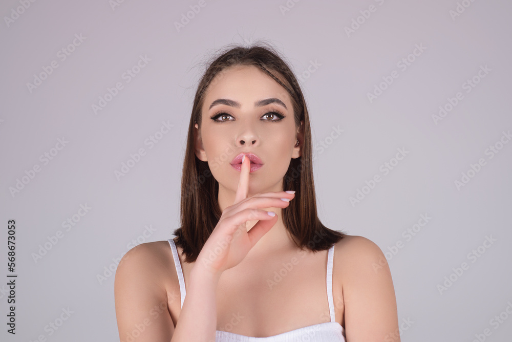 Beauty and silence concept. Portrait of attractive funny young lady showing shhh taboo sign with finger to lips over studio background, isolated. Shhh sign, facial expression, secret. Beauty and silence concept. Portrait of attractive funny young lady showing shhh taboo sign with finger to lips over studio background, isolated. Shhh sign, facial expression, secret.