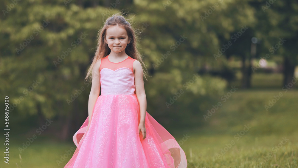Portrait of a little girl in a pink dress in the park