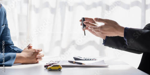 Car rental and Insurance concept, Young salesman giving car is key to customer after sign agreement contract with approved for rent or purchase.