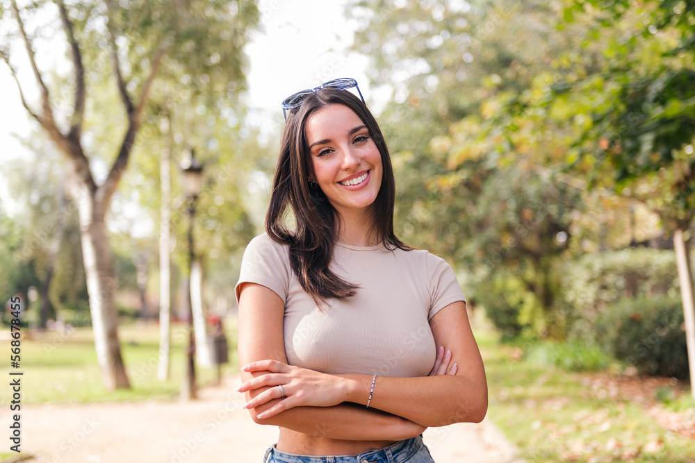 young caucasian woman with arms crossed looking at camera smiling with sunglasses on her head, concept of youth and beauty young caucasian woman with arms crossed looking at camera smiling with sunglasses on her head, concept of youth and beauty