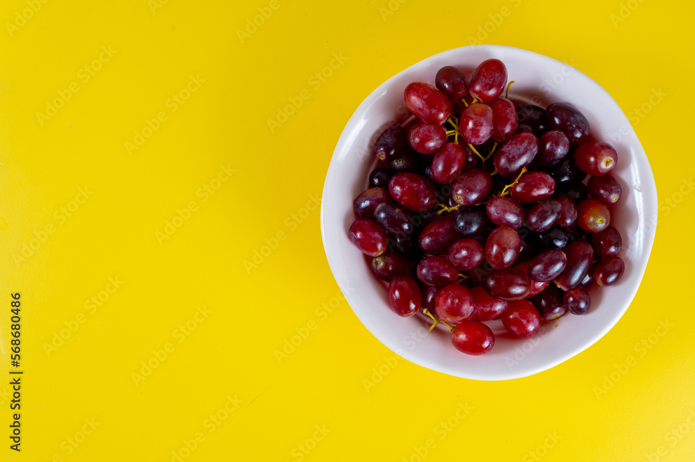 Red grapes on pink cup, yellow background Red grapes on pink cup, yellow background