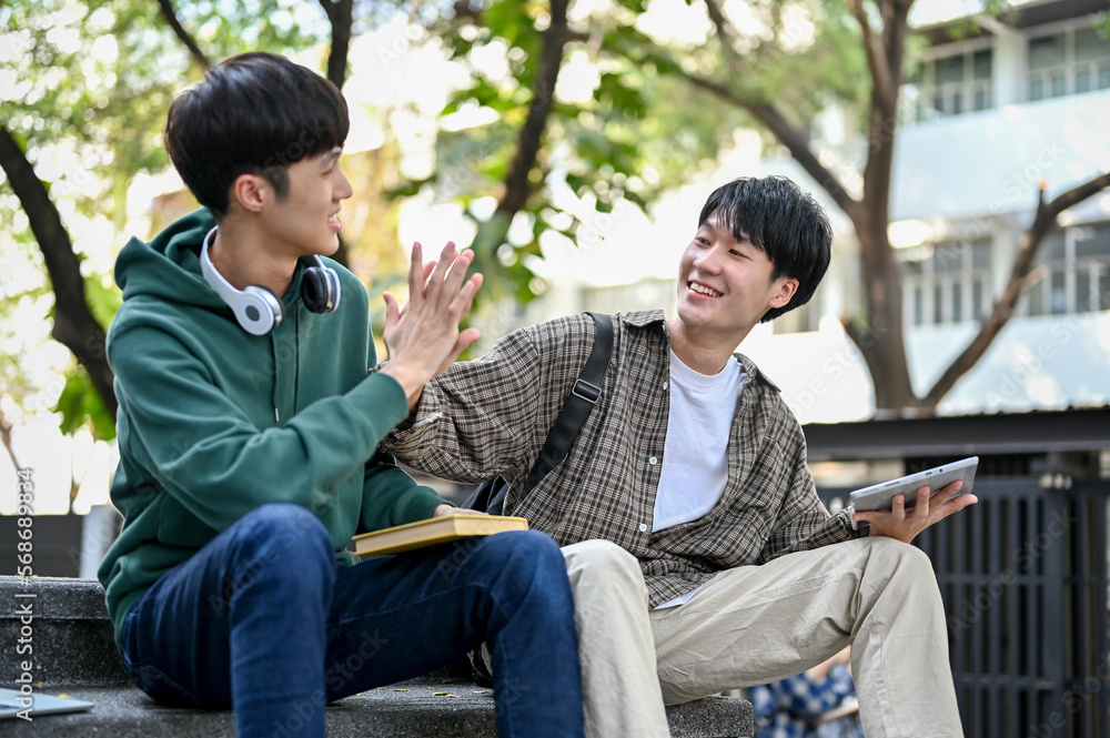 Cheerful young Asian male college student giving high five to his friend. friendship, best friend