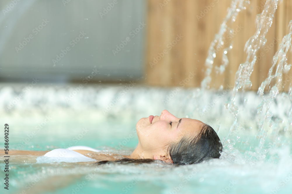 Happy woman relaxing floating in spa pool