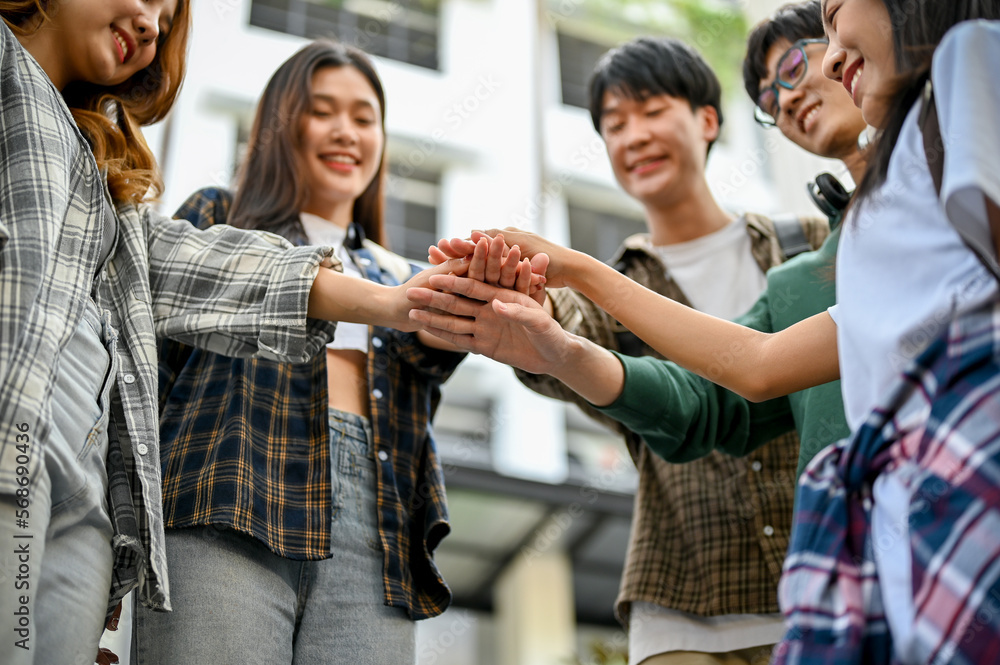 Obraz premium Group of cheerful Asian college students putting their hands together. friends, unity, teamwork