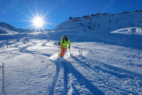 Austria, Tyrol, Sun shining over female skier sliding down snowcapped slope in Tux Alps photo