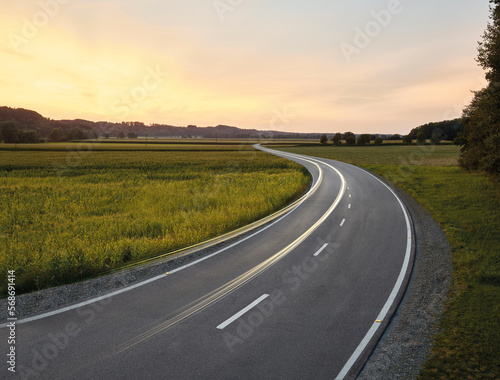 Austria, Vehicle light trails stretching along country road at dusk