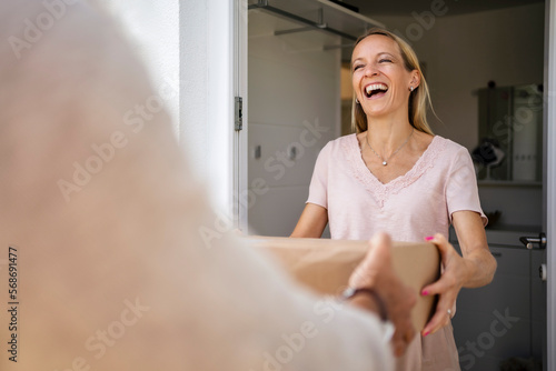 Laughing woman receiving parcel at the front door