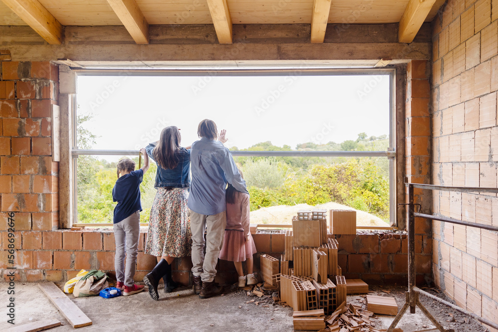 Mature man and woman with daughters looking through window Mature man and woman with daughters looking through window