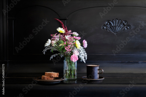 Mug of coffee, cake bouquet of seasonal flowers lying on piano