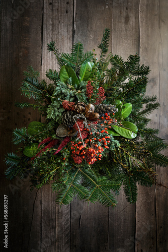 Autumnal arrangement of twigs, laurel, amaranthus, skimmia, rose hips and pine cones photo