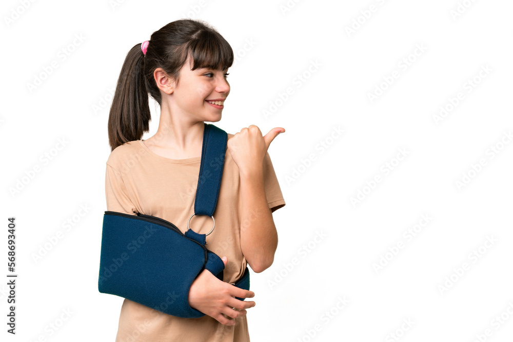 Little caucasian girl with broken arm and wearing a sling over isolated background pointing to the side to present a product Little caucasian girl with broken arm and wearing a sling over isolated background pointing to the side to present a product