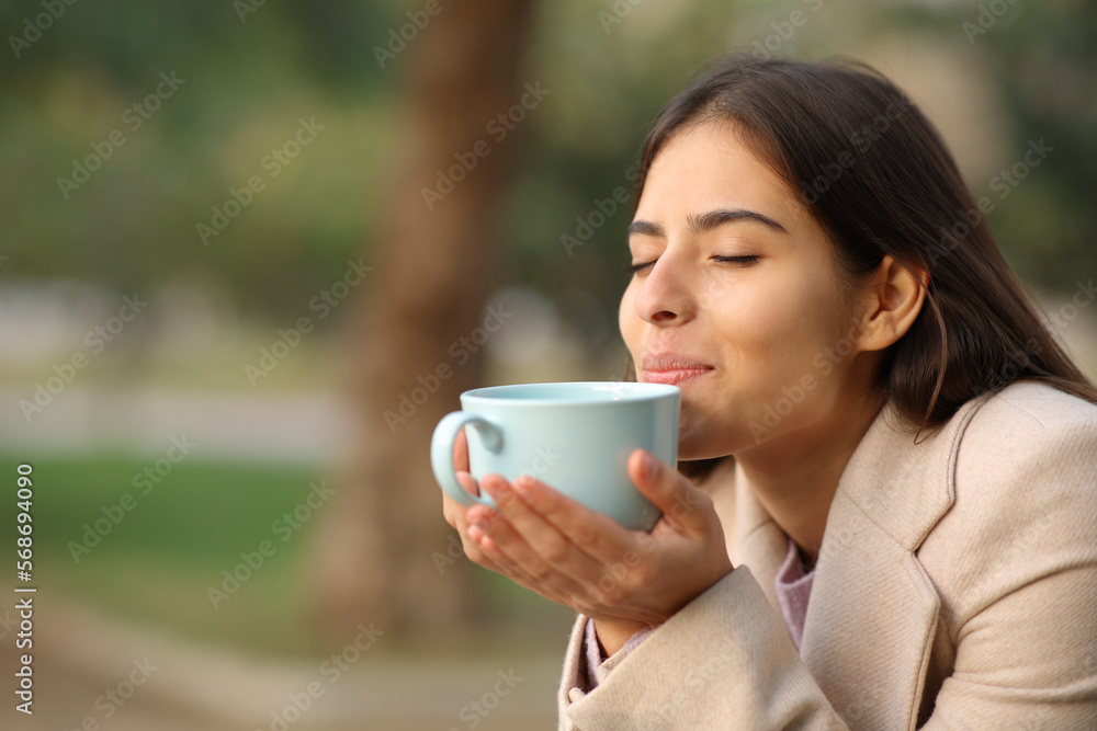 Woman at sunset in winter smelling coffee Woman at sunset in winter smelling coffee