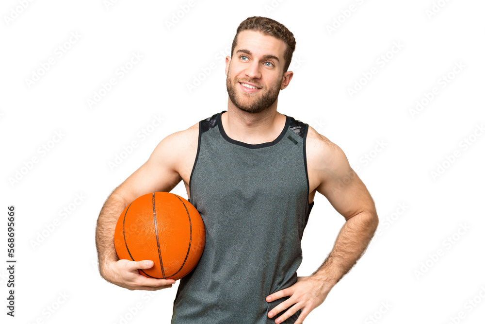 Handsome young man playing basketball over isolated chroma key background posing with arms at hip and smiling