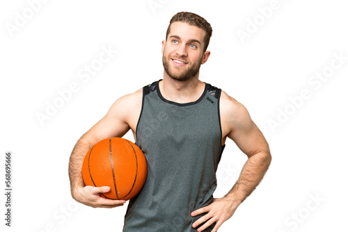 Handsome young man playing basketball over isolated chroma key background posing with arms at hip and smiling © luismolinero