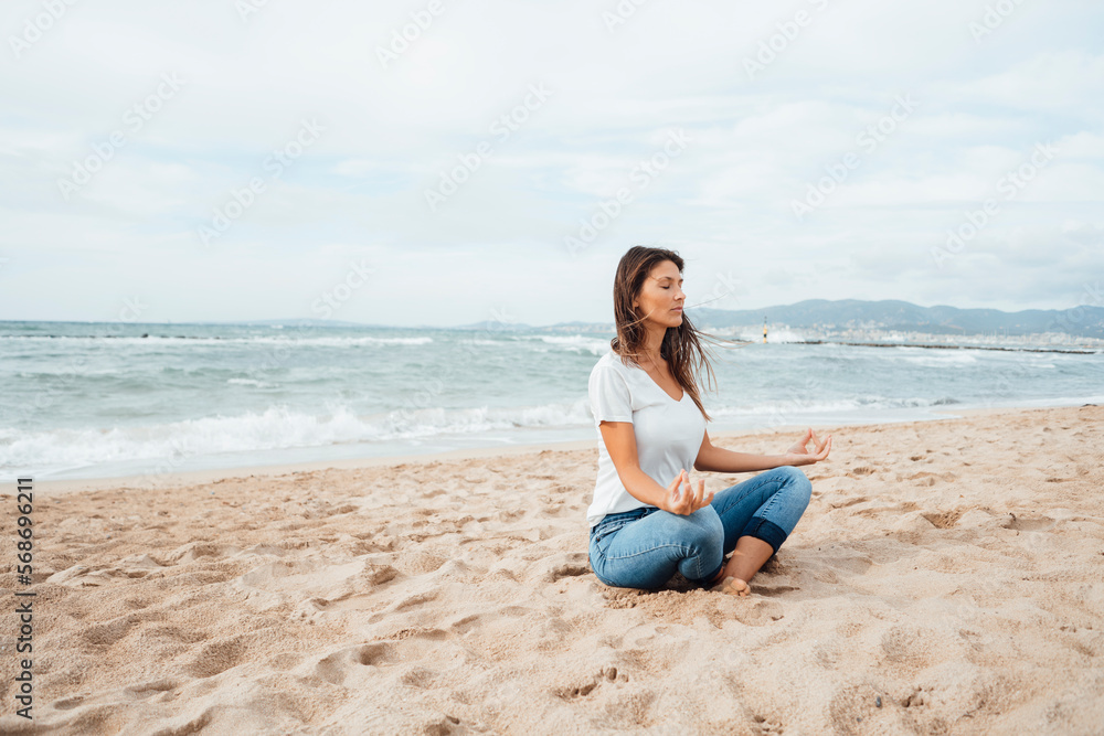 Woman doing yoga sitting on sand at beach Woman doing yoga sitting on sand at beach