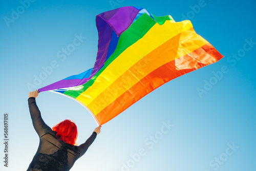 Woman on her back with open arms waving an lgbt flag photo