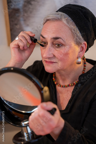 Woman in skullcap applying mascara at home photo