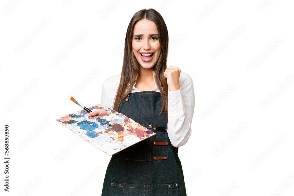 Young artist woman holding a palette over isolated chroma key background celebrating a victory in winner position Young artist woman holding a palette over isolated chroma key background celebrating a victory in winner position