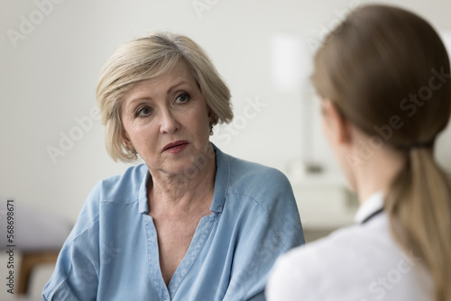 Serious older patient woman visiting doctor  getting geriatric health problems after medical checkup  listening to practitioner explaining diagnosis  giving treatment  therapy recommendation