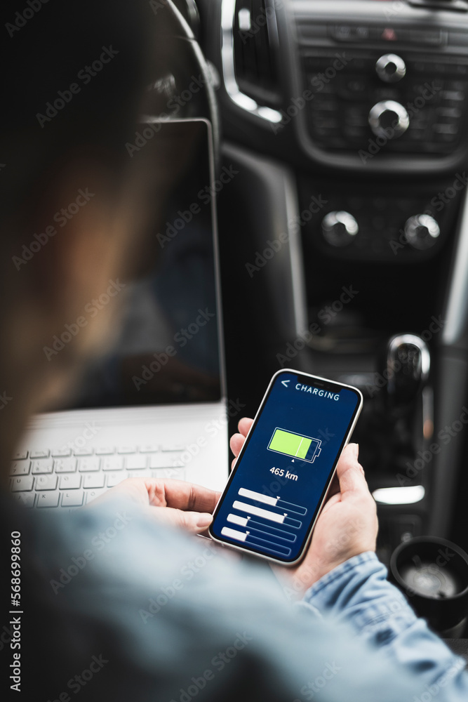 Woman using electric car charging app on mobile phone Woman using electric car charging app on mobile phone
