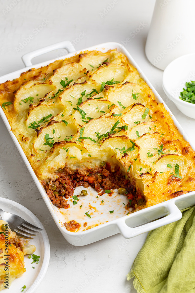 English Shepherd's pie, or cottage pie, or French version hachis Parmentier.  Cooked minced beef meat with vegetables, green pea, carrot, onion, topped  with mashed potato with cheese and baked. Photos | Adobe