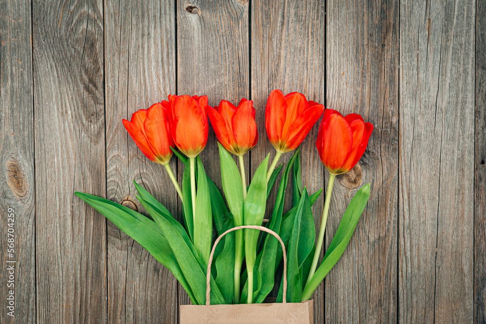 Bouquet of red tulips on a wooden background, top view.