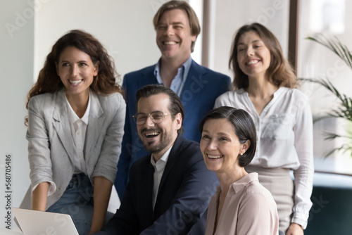 Happy diverse multiethnic business team posing for shooting together  sitting  standing at office workplace  looking away  smiling  laughing. Millennial work group candid portrait