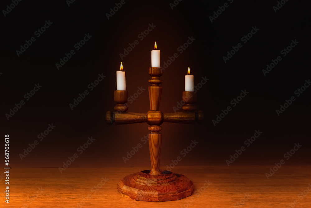 Candlestick,Candle flames on a wooden table dark background, symbol of prayer and remembrance.Religion concept. Candlestick,Candle flames on a wooden table dark background, symbol of prayer and remembrance.Religion concept.