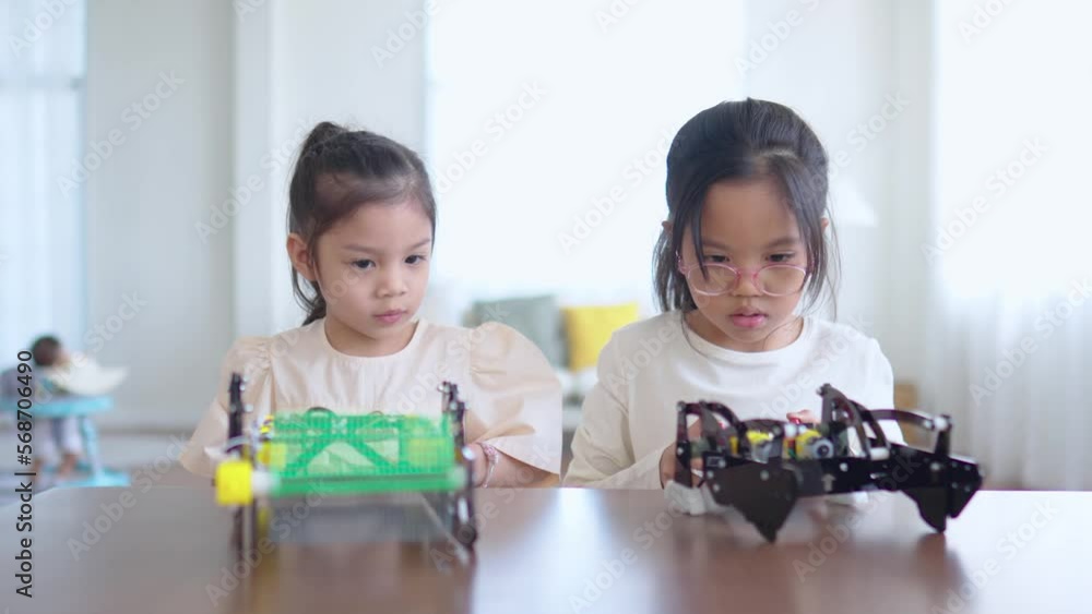 Two Asian child girl control robotic car at the table had so much fun and happiness. Technology with smart toys concept. Two Asian child girl control robotic car at the table had so much fun and happiness. Technology with smart toys concept.