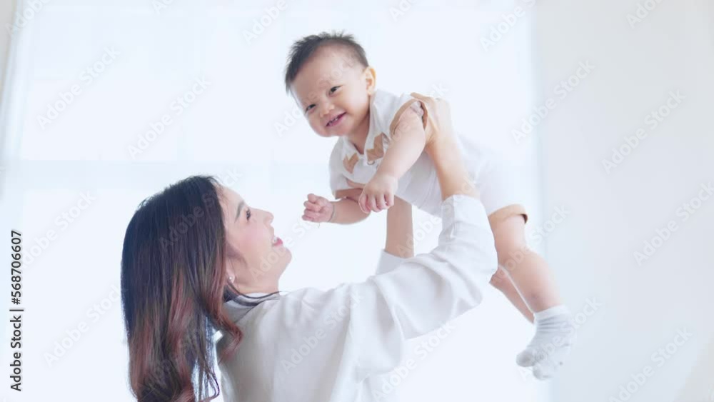 Happy mother throws baby up, laughing and playing in bedroom. Happy mother throws baby up, laughing and playing in bedroom.